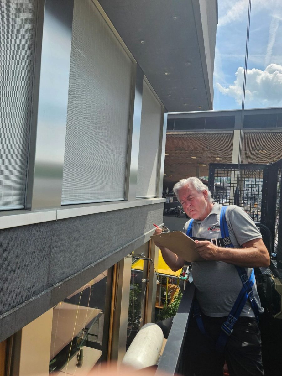 Handwerker montiert Fassadenelement am Fensterrahmen