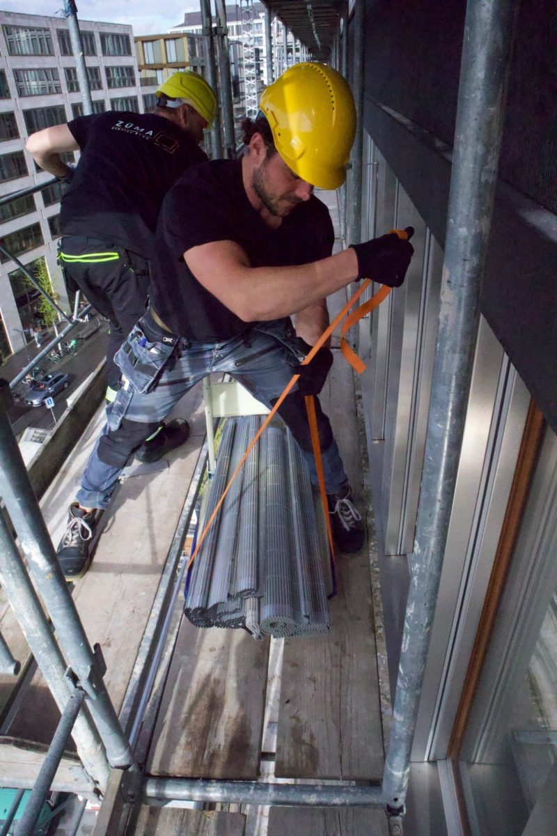 Handwerker mit gelbem Helm arbeitet am Metallrahmen