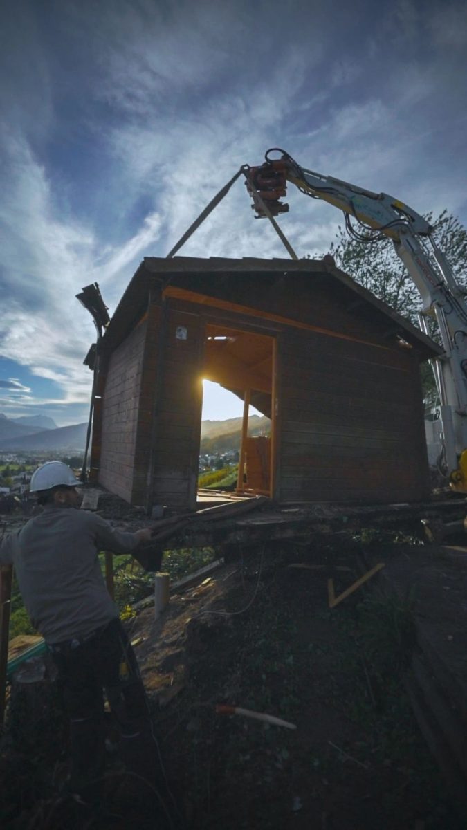 Kran versetzt kleines Holzhaus; Abendlicht im Innenraum
