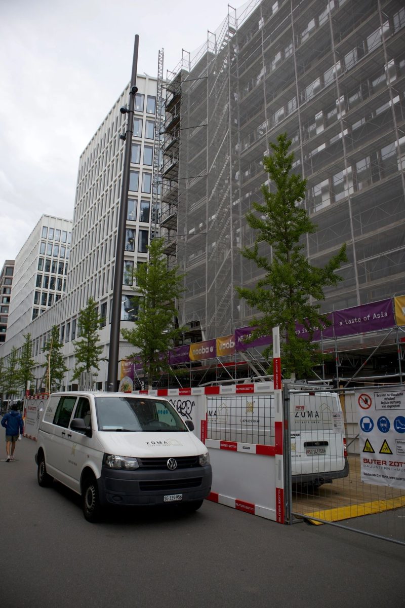 Eingerüstete Fassade an Stadtstraße mit Lieferwagen